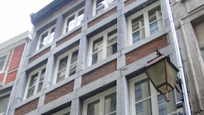 Un edificio de varios pisos con fachada de ladrillo y ventanas con marcos blancos.