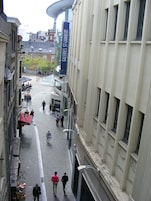 Una calle adoquinada flanqueada por edificios, un cartel que indica Galerie St. Lambert, y gente caminando.