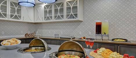 A buffet setup with various food items and a drink station.