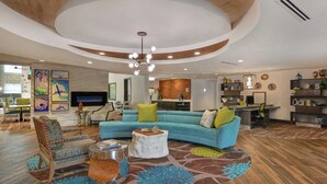 A spacious living room with a curved ceiling, a sectional sofa, a wooden chair, and a round coffee table. - Homewood Suites by Hilton Savannah-North/Airport (Savannah)