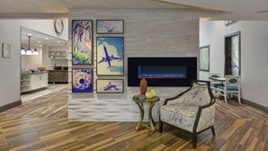 A modern living room with a fireplace, artwork on the walls, and a dining area with chairs and a table. - Homewood Suites by Hilton Savannah-North/Airport (Savannah)