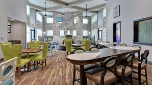 A hotel lobby with a large conference table, green and brown chairs, and a patterned carpet. - Homewood Suites by Hilton Savannah-North/Airport (Savannah)