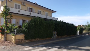 Um edifício de dois andares com fachada amarela, persianas brancas e vários aparelhos de ar condicionado.