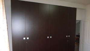 Guarda-roupa de madeira escura com duas puxadores visíveis e uma porta branca.