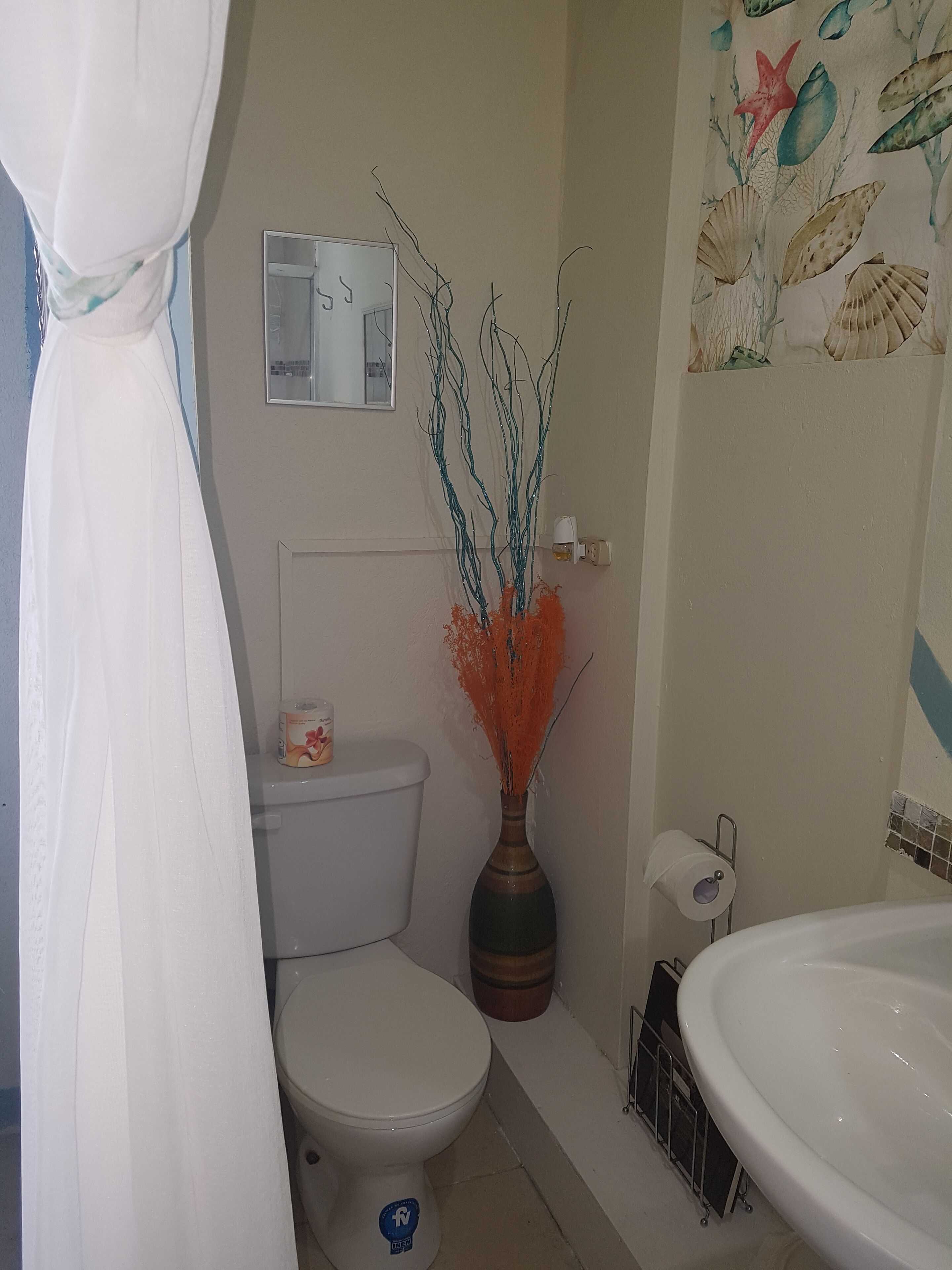 A bathroom with a toilet, a sink, and a shower curtain.