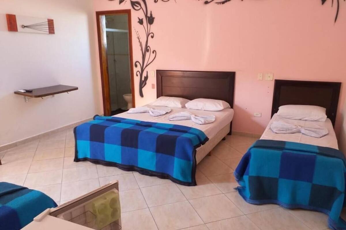Une chambre d’hôtel avec deux lits, une petite table et un miroir.