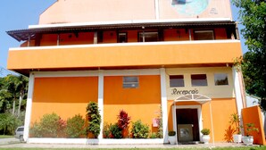 Un edificio con una recepción, un mural grande en la pared lateral y plantas en macetas al frente.