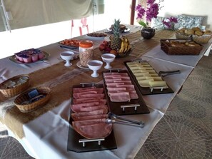 A buffet table with various food items including meats, fruits, and condiments. - Hotel Sol de Pernambuco (Guarujá)