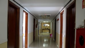 Un pasillo con puertas de madera a ambos lados, suelo de baldosas e iluminación empotrada en el techo.