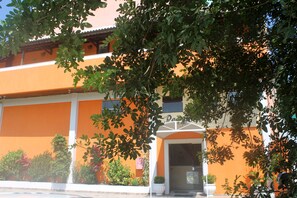 A building with an orange facade, a white entrance, and potted plants around the entrance. - Hotel Sol de Pernambuco (Guarujá)