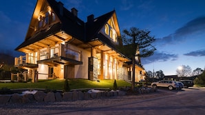 A large, modern house with a prominent balcony and a well-lit entrance. - Rezydencja Zakopiańska (Zakopane)