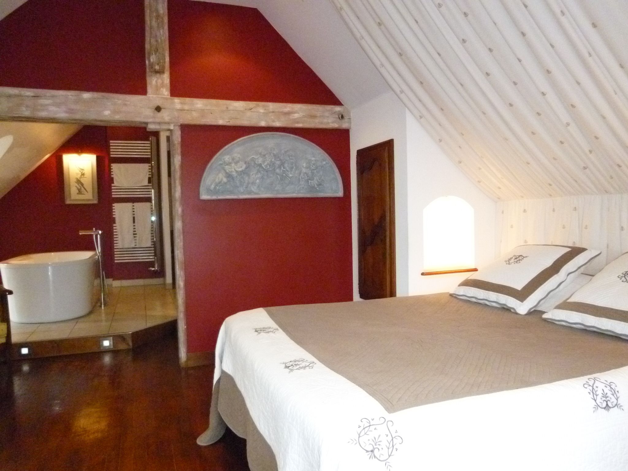 Un dormitorio con una cama grande, una bañera y un techo inclinado.