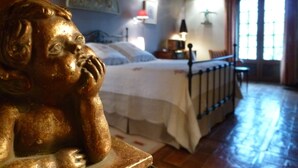 A bedroom with a bed, a nightstand, a lamp, and a window with curtains. - Chambres d'hôtes au clos de Beaulieu (Bossée)
