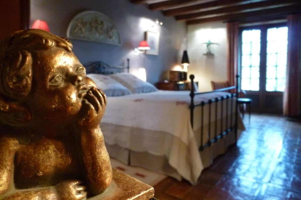 A bedroom with a bed, a nightstand, a lamp, and a window with curtains.