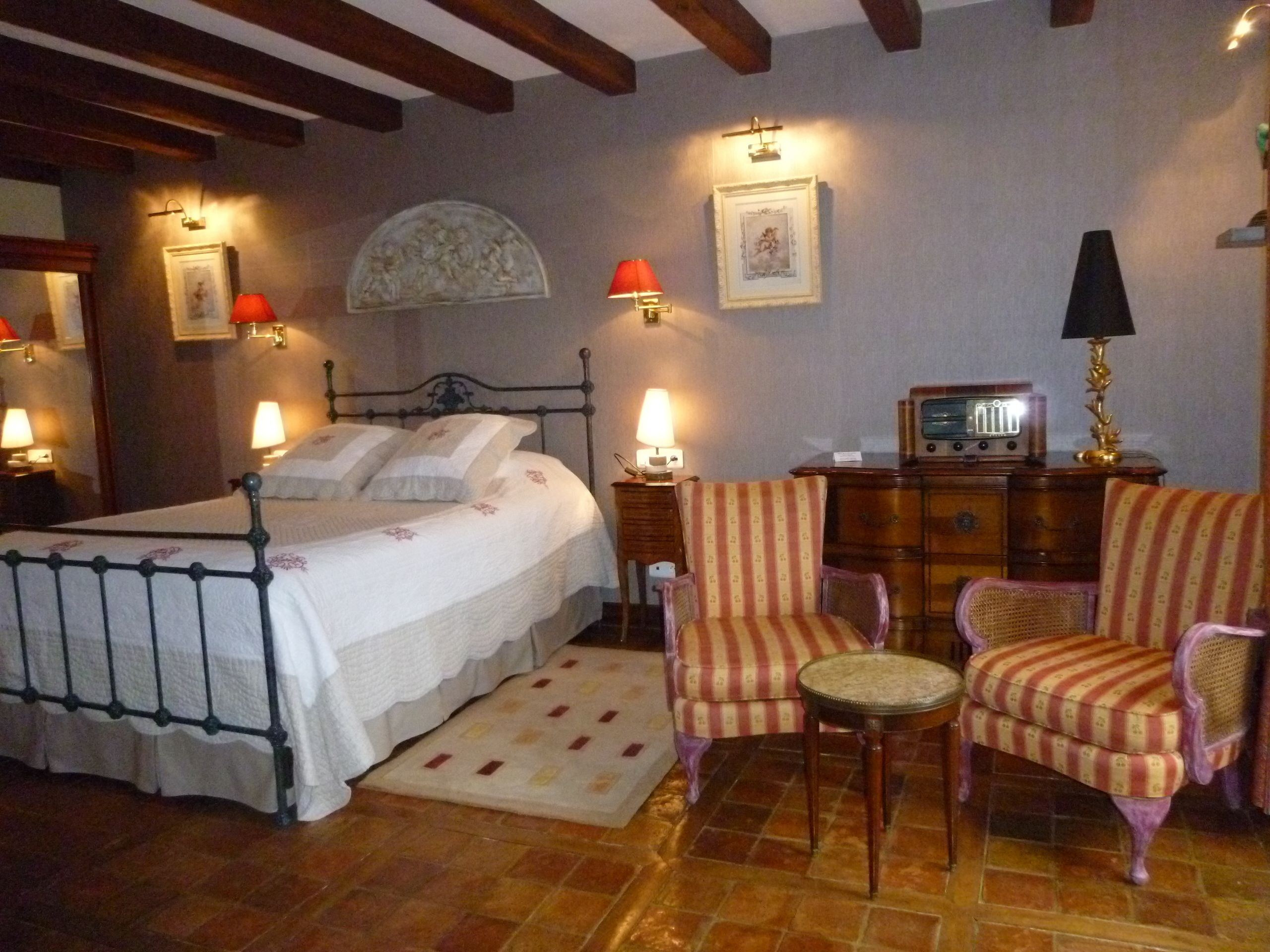 Ein Schlafzimmer mit einem Bett, zwei Stühlen, einem Schminktisch und einem Radio.
