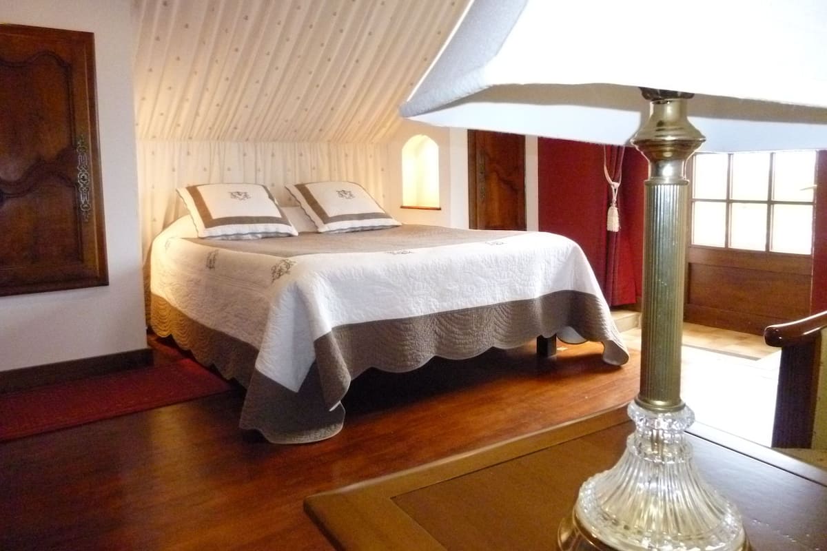 A bedroom with a bed, a lamp, and a window.