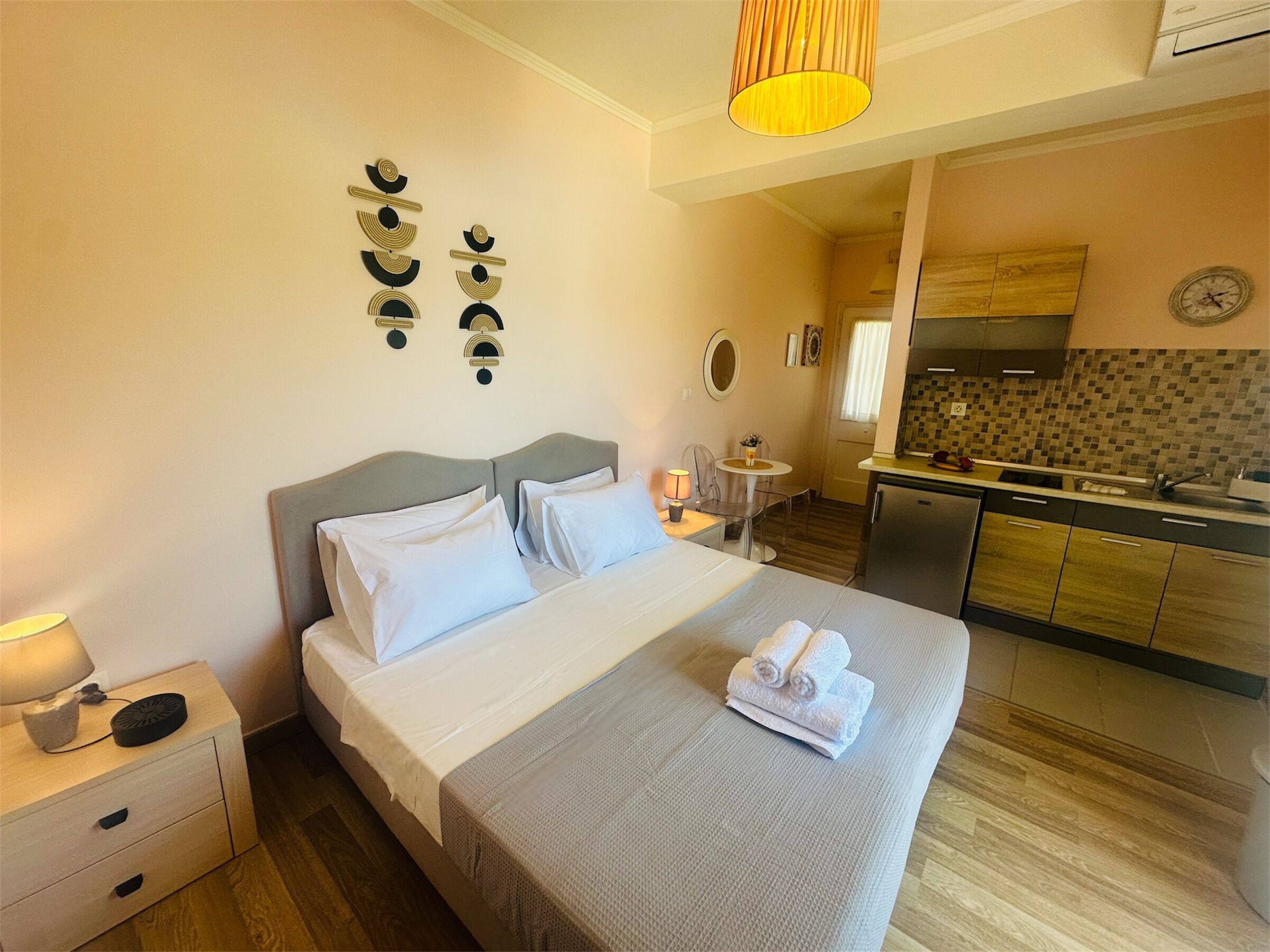Une chambre d’hôtel équipée d’un lit, d’une table de chevet, d’une lampe et offrant une vue sur la cuisine et la salle de bain.