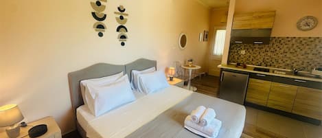 Et hotelværelse med seng, natbord, lampe samt udsigt til køkken og badeværelse.