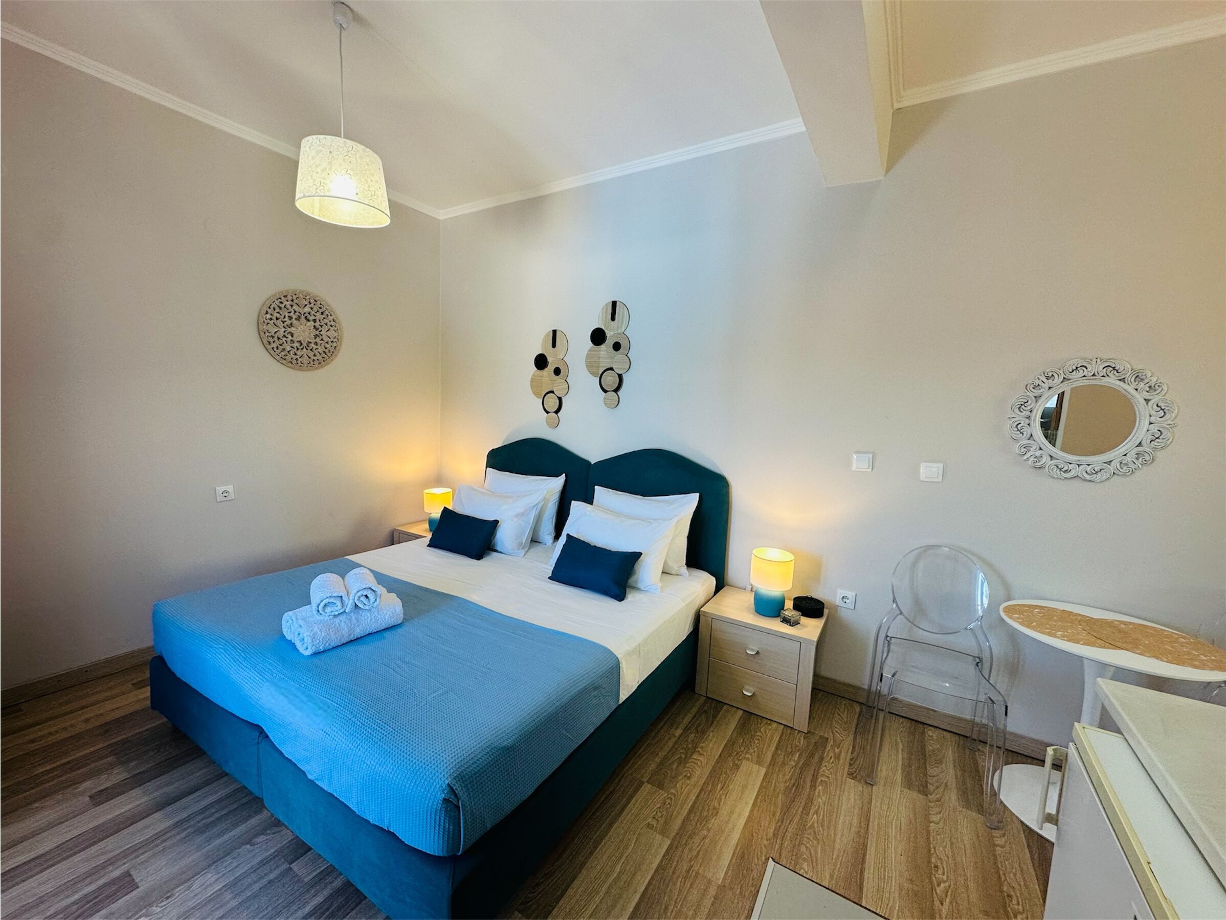 A neatly arranged bedroom with a bed, bedside tables, a desk, and a chair.