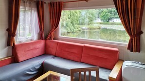Una habitación con un sofá rojo, una silla de madera y una mesa con un control remoto.