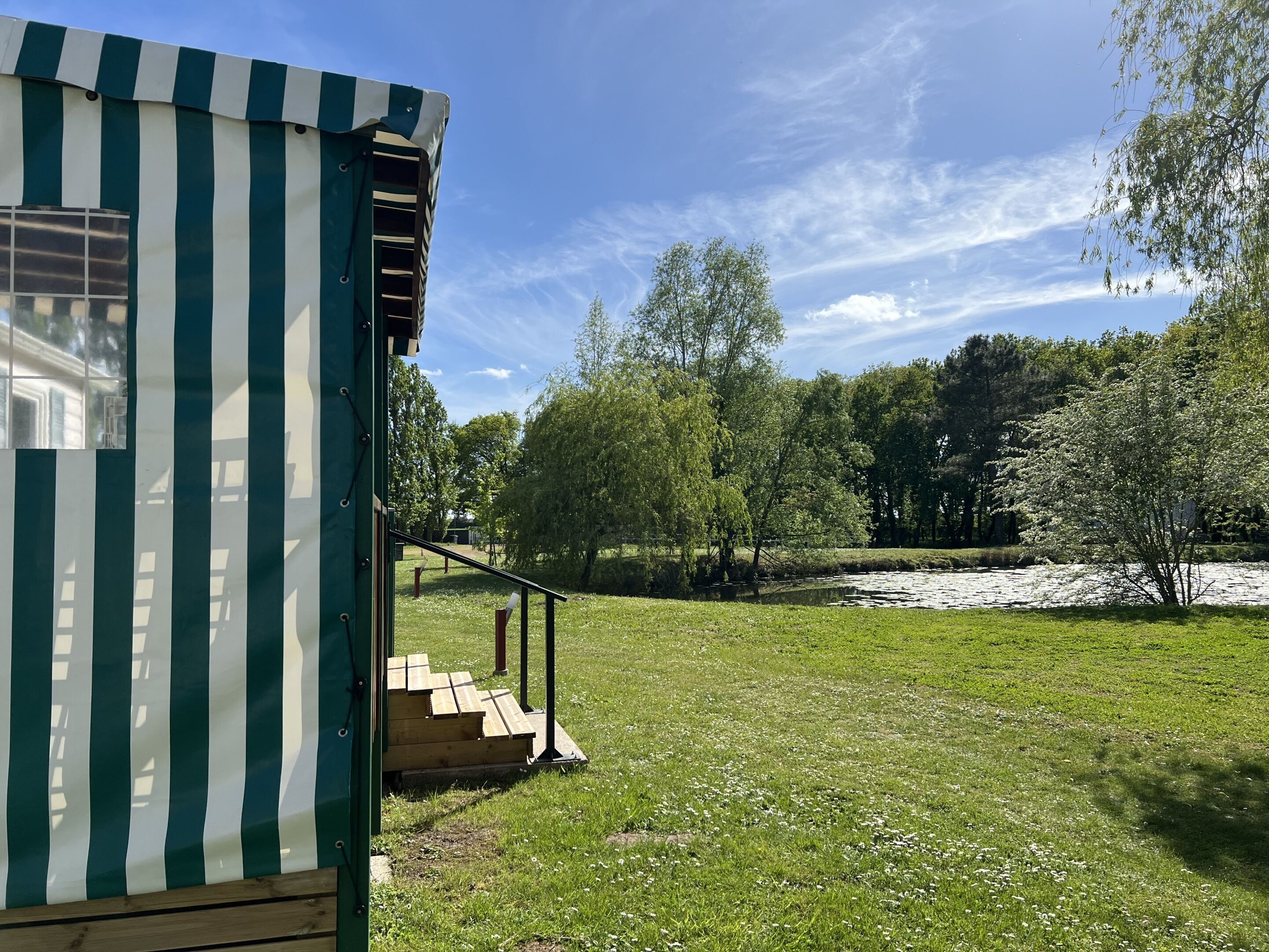 A green and white striped building with a ramp leading to a wooden platform.