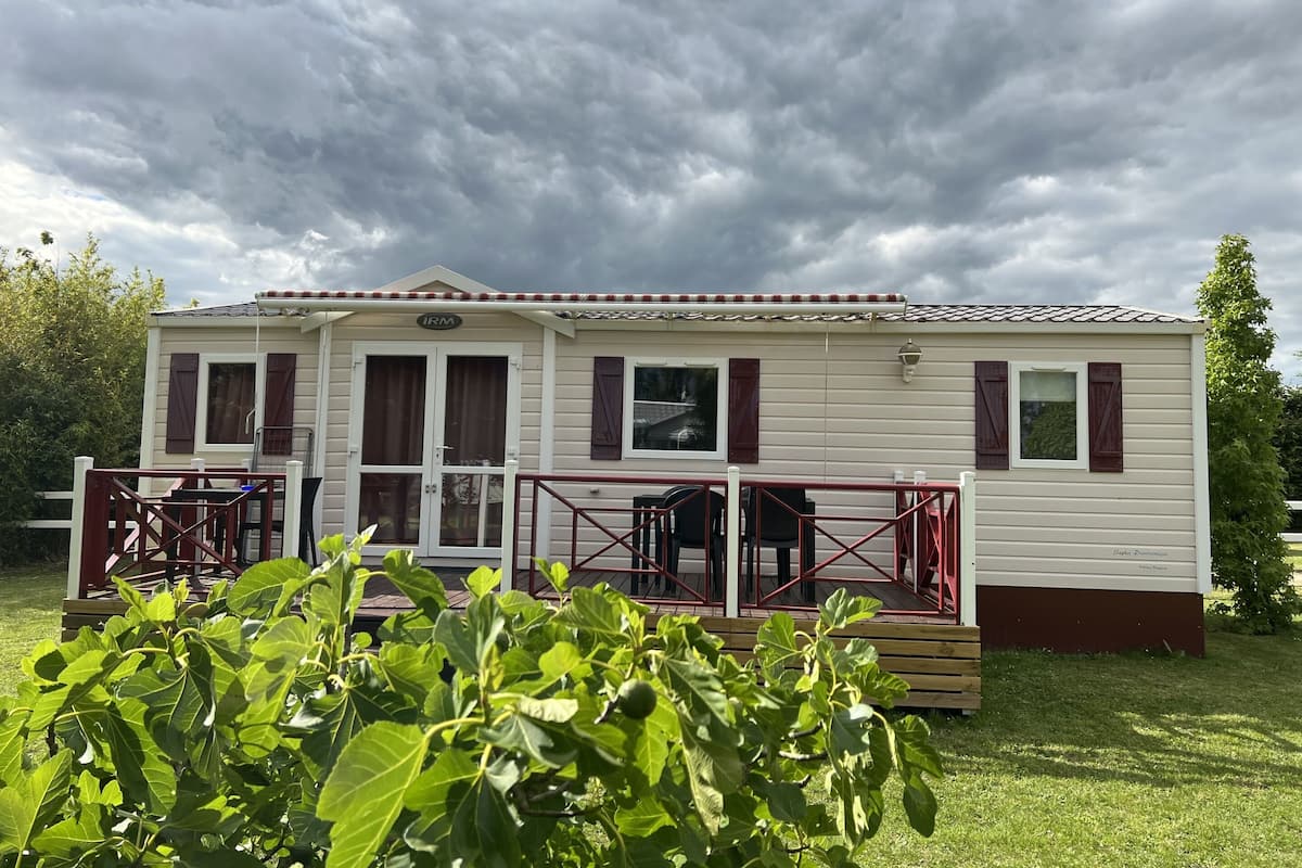 Una casa móvil con un porche, una zona de estar al aire libre techada y un pequeño jardín delantero.