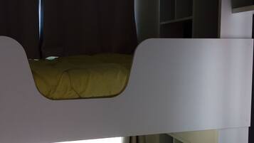 Een stapelbed met een gele matras en een raam met gordijnen.