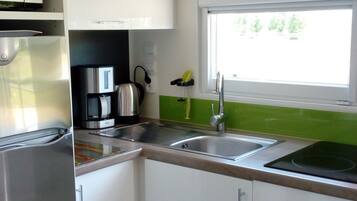Una cucina moderna con un frigorifero in acciaio inox, una macchina da caffè e un lavello con una finestra sopra.