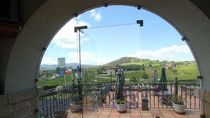 A balcony with a view of a green landscape, including hills and a flag. - Posada El Iso (Santillana del Mar)