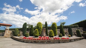 A landscaped garden with neatly trimmed hedges and a variety of flowering plants. - Posada El Iso (Santillana del Mar)