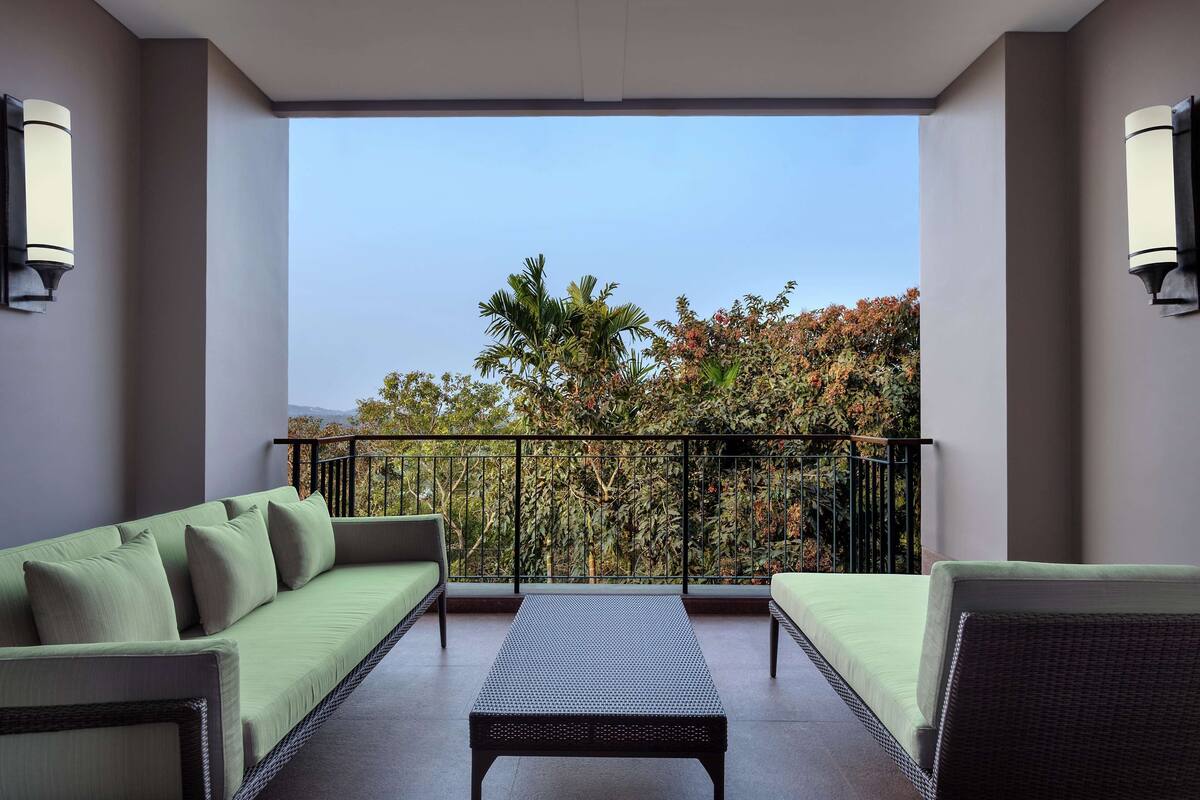 A balcony with a green sofa, a small table, and two chairs.