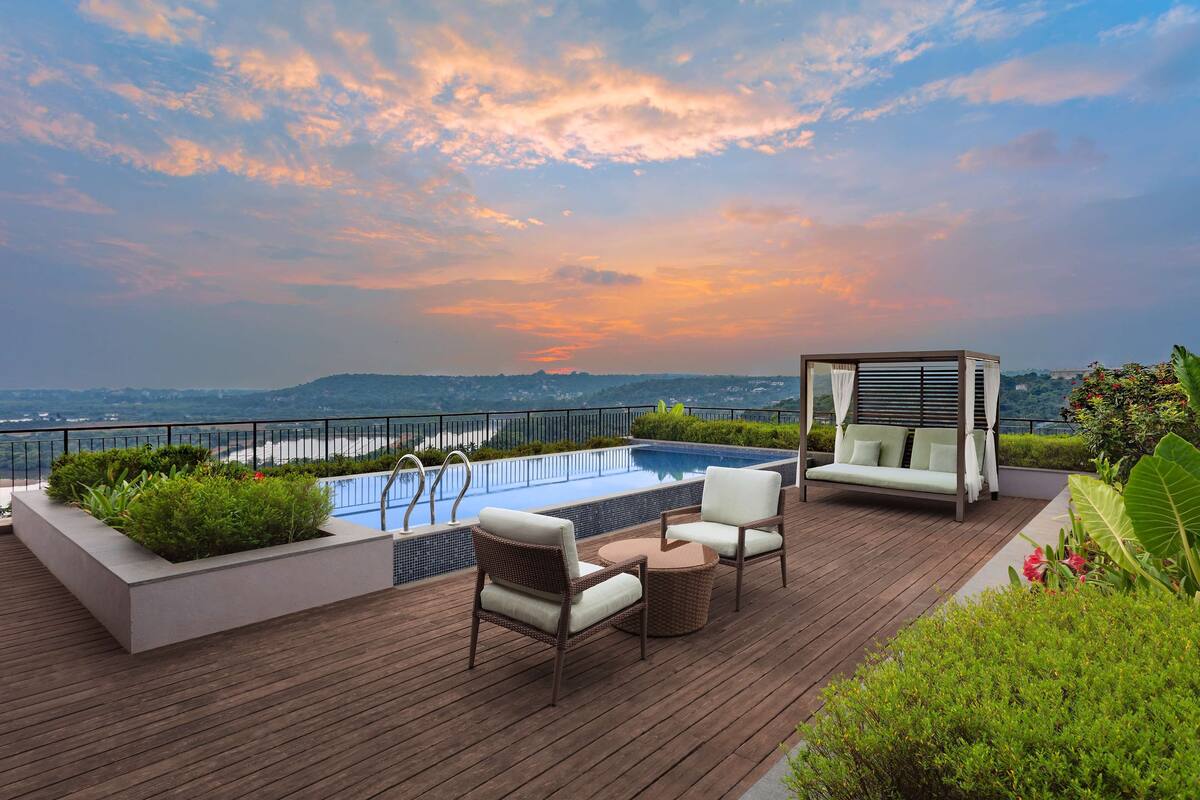 A rooftop pool area with a view of the city skyline, a wooden deck, and a seating area with a canopy.