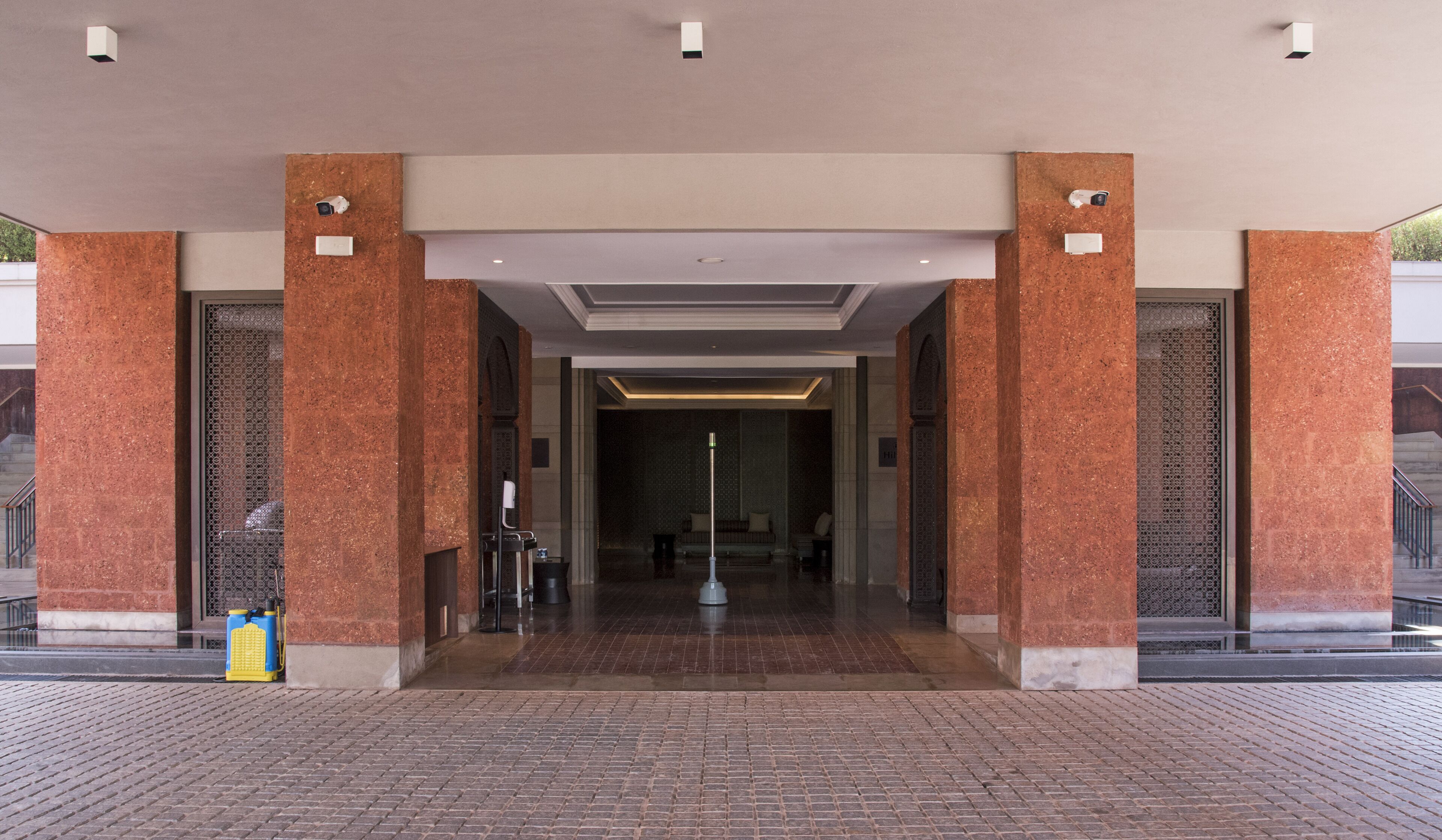 A hotel entrance with a modern design, featuring a central pathway leading to a seating area.