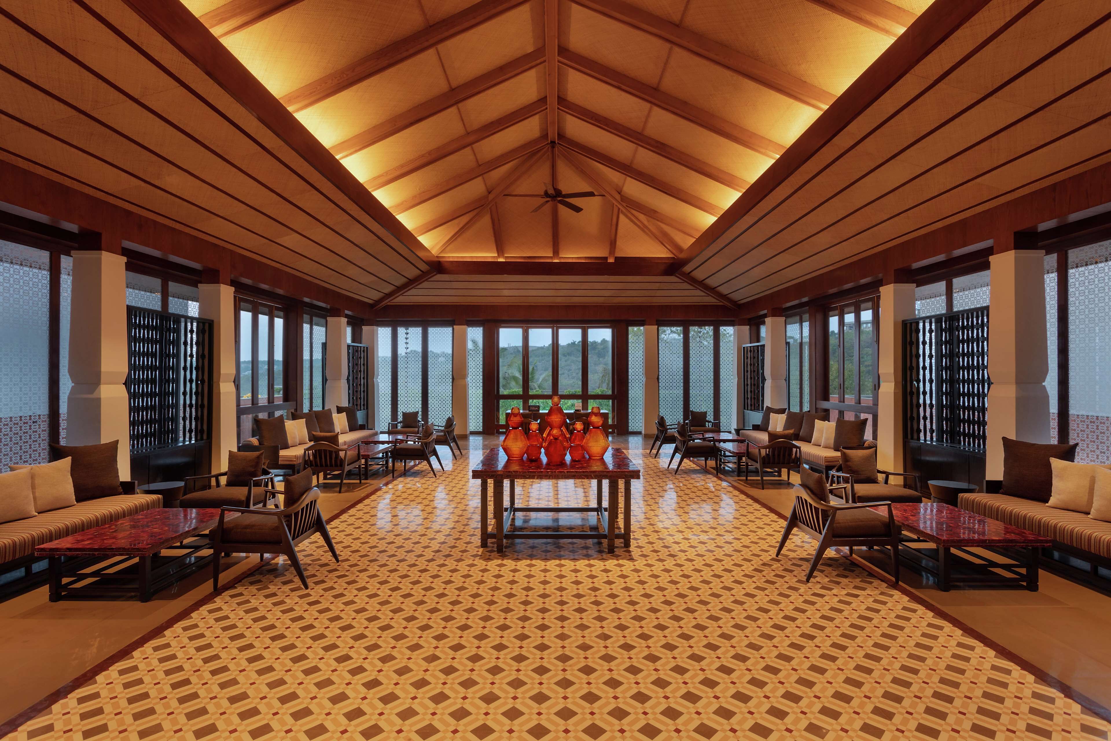 A spacious lobby with a high ceiling, a central table with decorative vases, and seating arrangements.