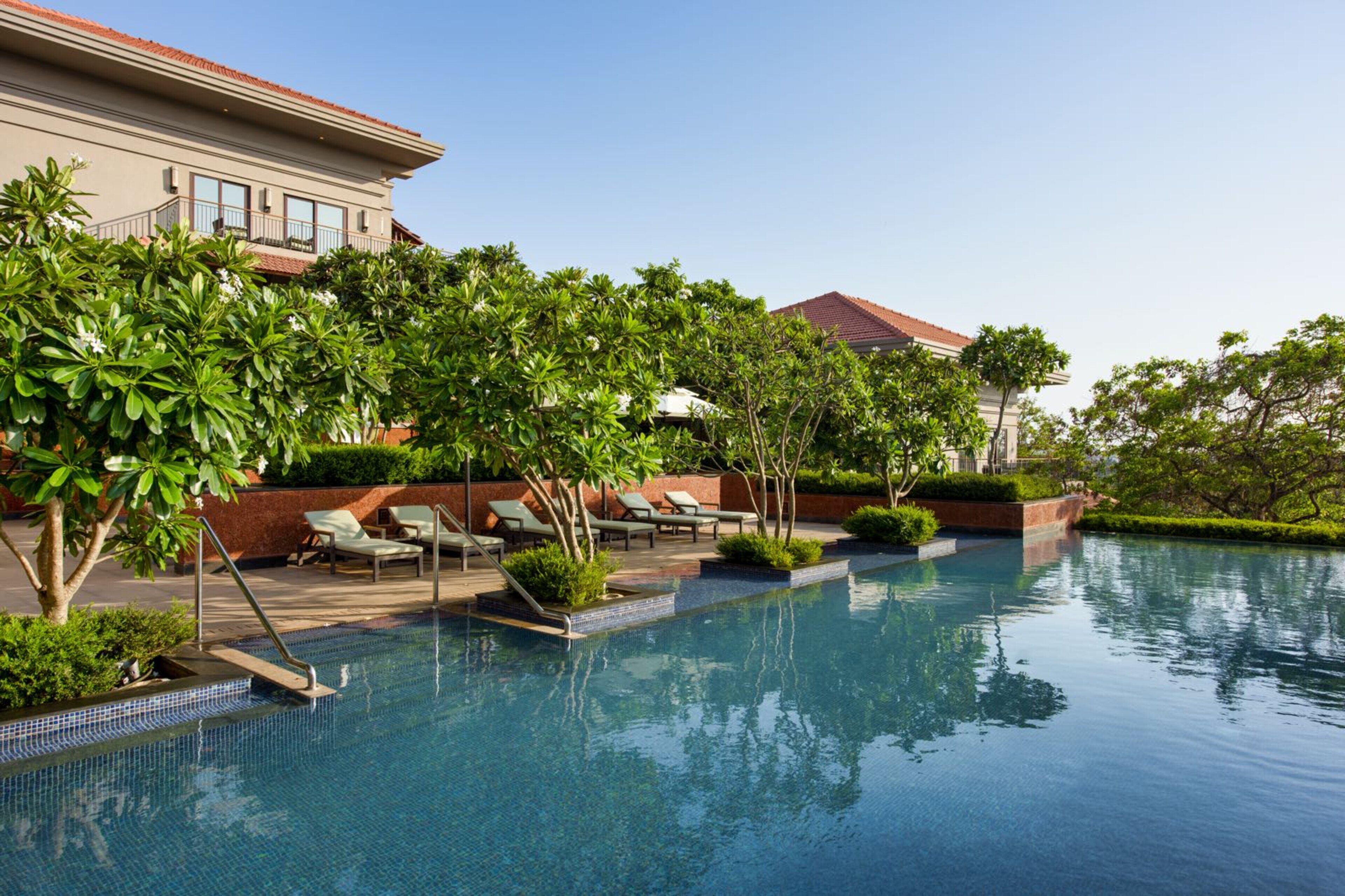 A pool area with lounge chairs and a building in the background.