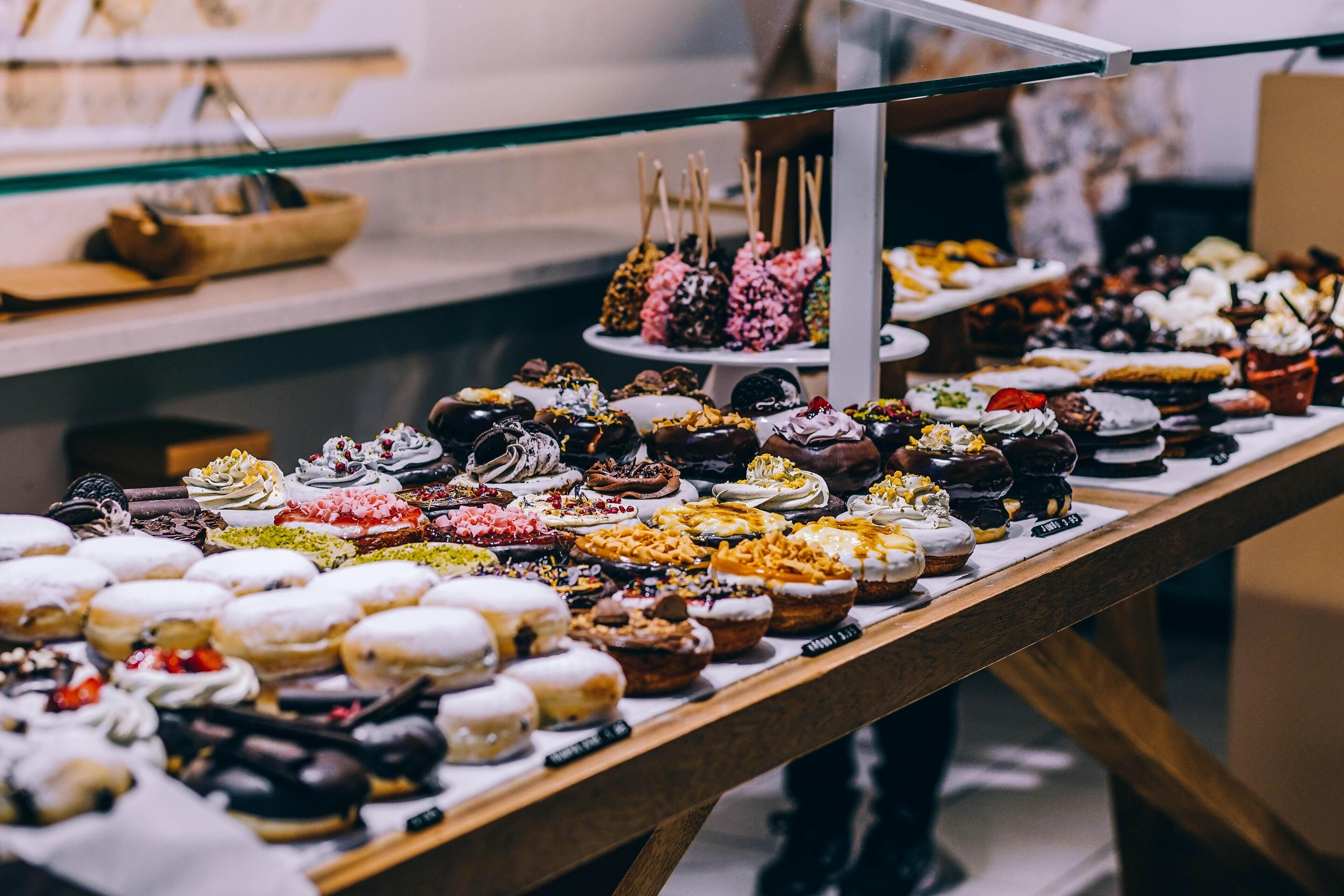 A variety of desserts displayed on a counter with a glass barrier.