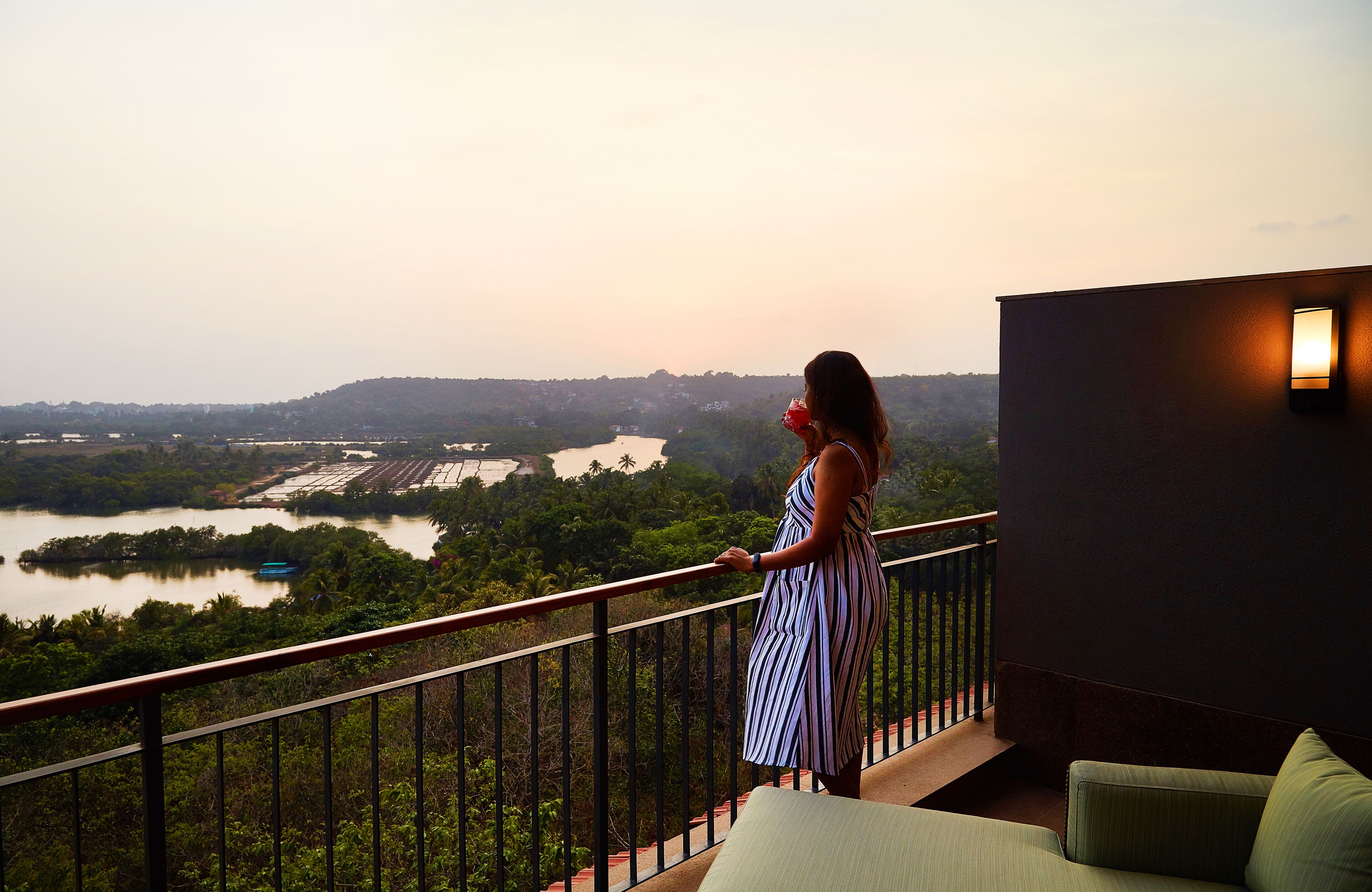 A balcony with a view of a river and hills.