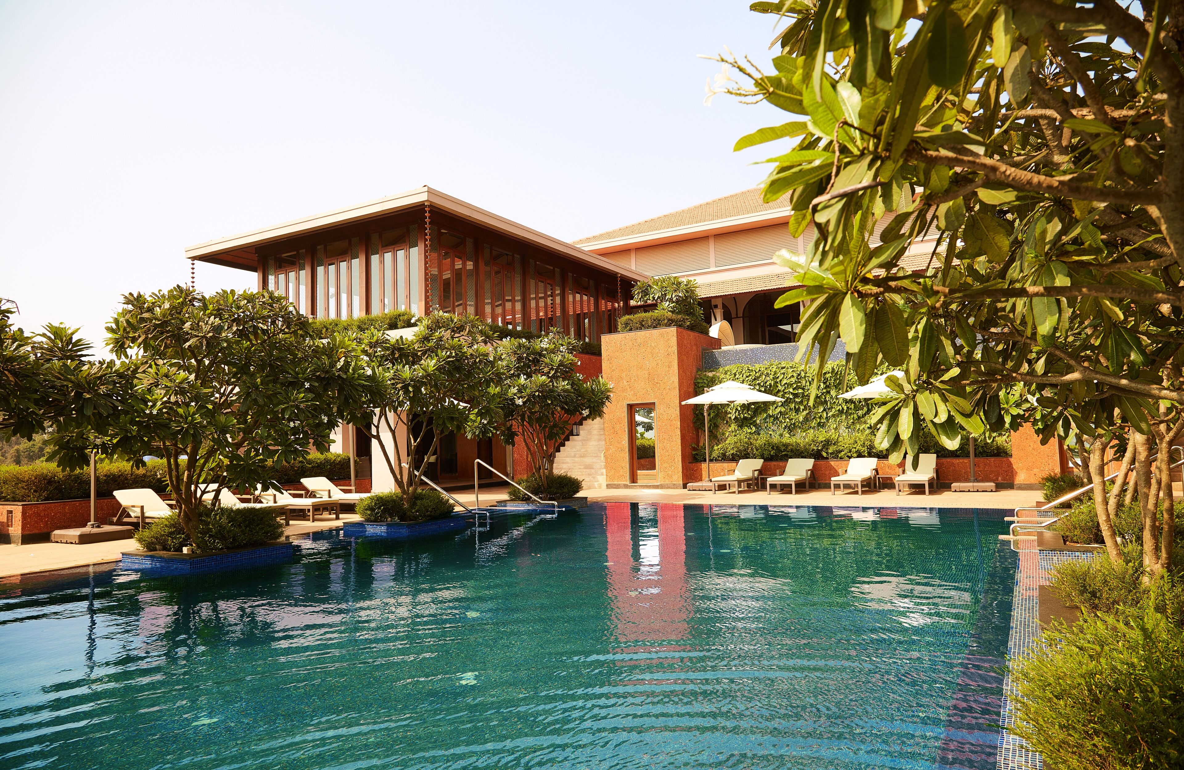 A pool area with lounge chairs and a building with large windows and a covered patio.