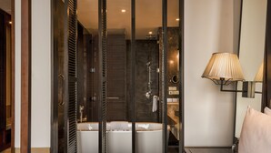 A modern bathroom with a bathtub, shower, and a large mirror. - Hilton Goa Resort Candolim (Candolim)