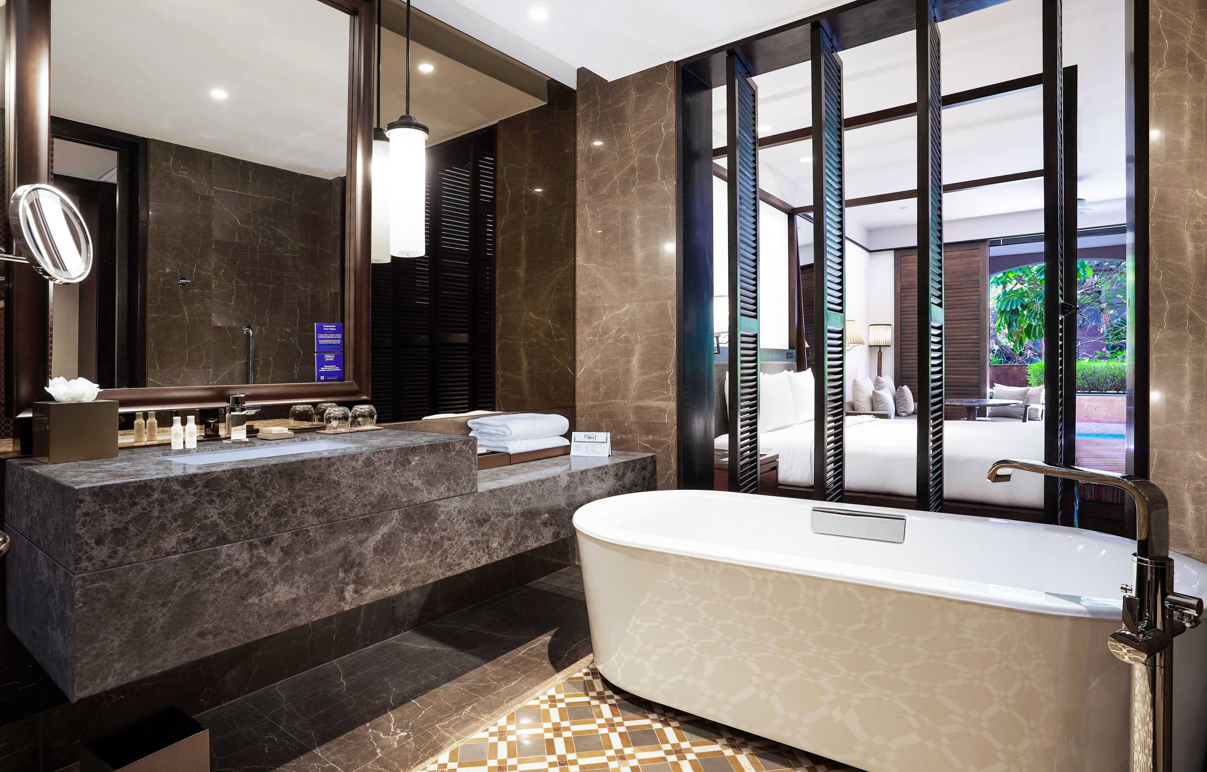 A modern bathroom with a large mirror, a bathtub, and a vanity with toiletries.