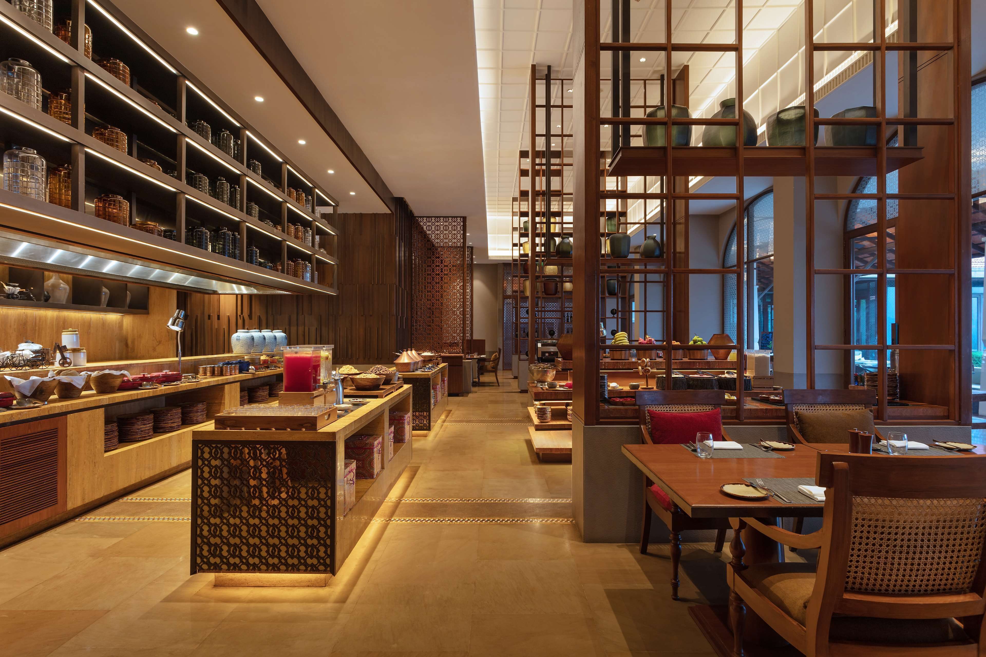 A restaurant with wooden furniture, shelves with dishes, and a patterned partition.