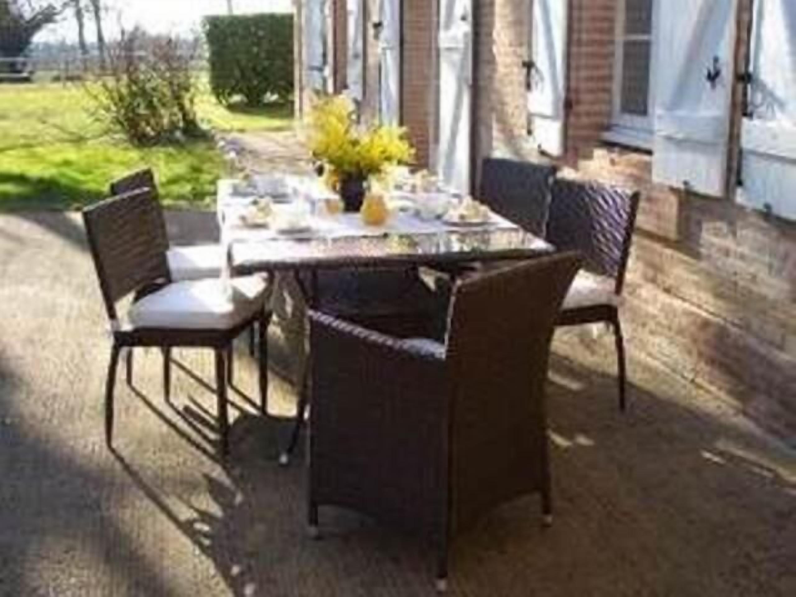 An outdoor dining area with a table set for four, surrounded by wicker chairs.