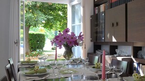 Mesa de comedor preparada para una comida, con vistas a la vegetación.