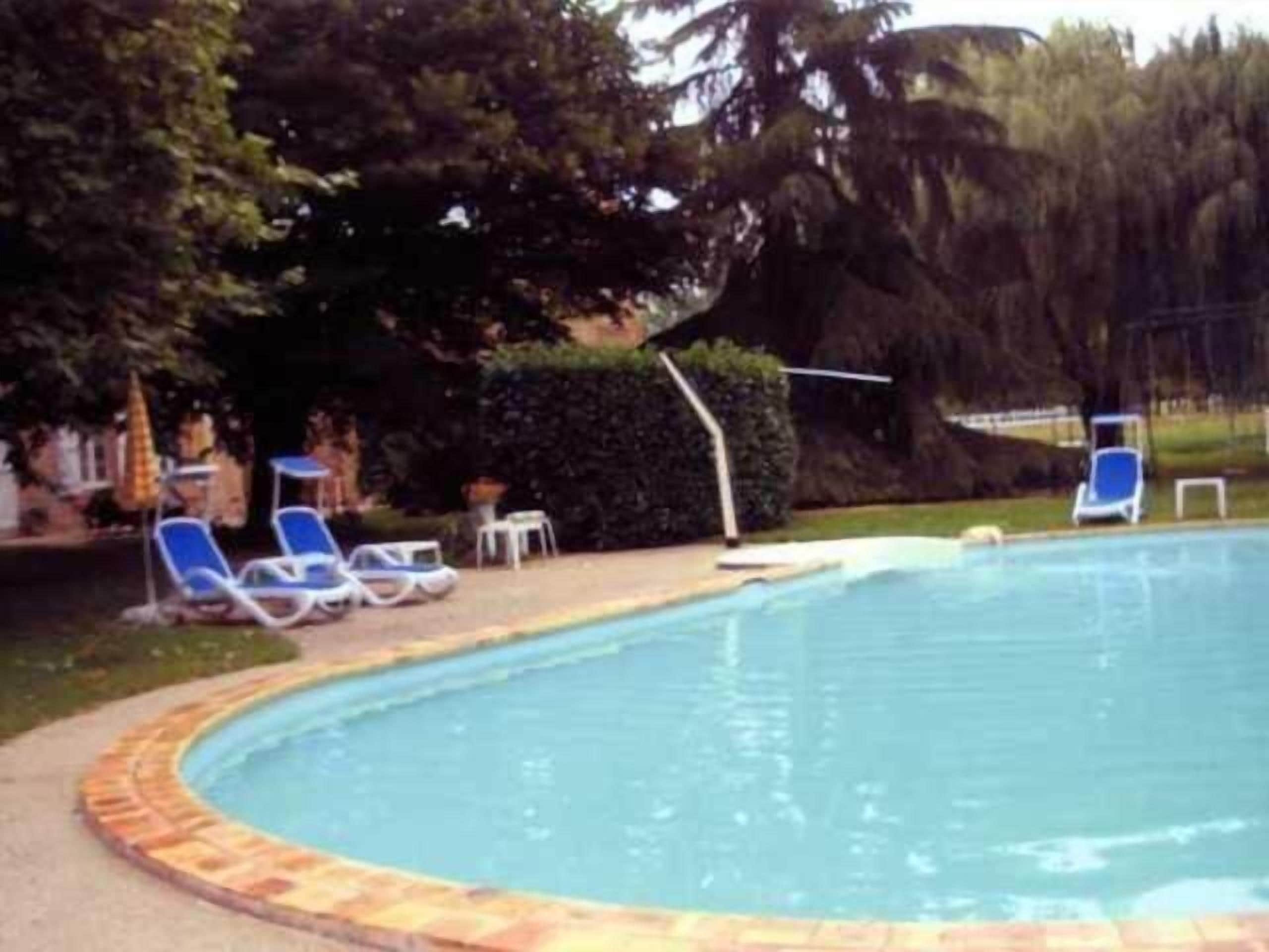A swimming pool with blue lounge chairs and a brick border.