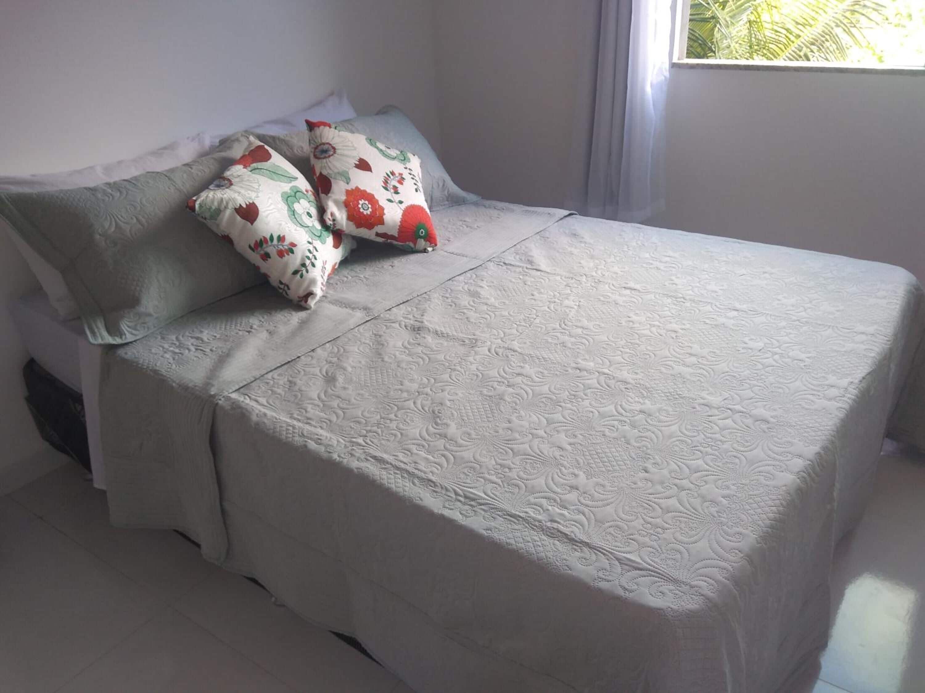 A bed with a patterned bedspread and two pillows with floral designs.