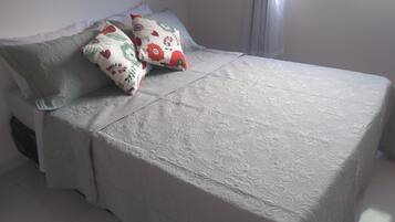 A bed with a patterned bedspread and two pillows with floral designs.