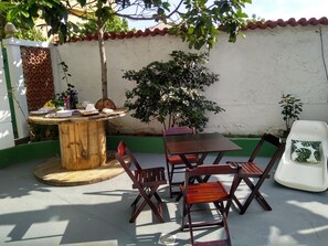 A patio with a wooden table, chairs, and a small tree. - Pousada Arraial Caribe (Arraial do Cabo)