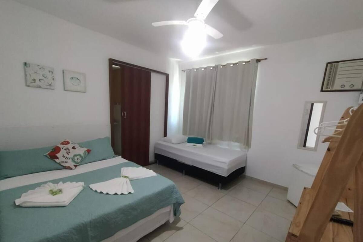 A bedroom with two beds, a ceiling fan, a window with curtains, and a wooden chair.