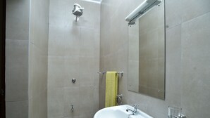 Ein Badezimmer mit Waschbecken, Spiegel, Handtuchhalter, Dusche und einem Glas Wasser.