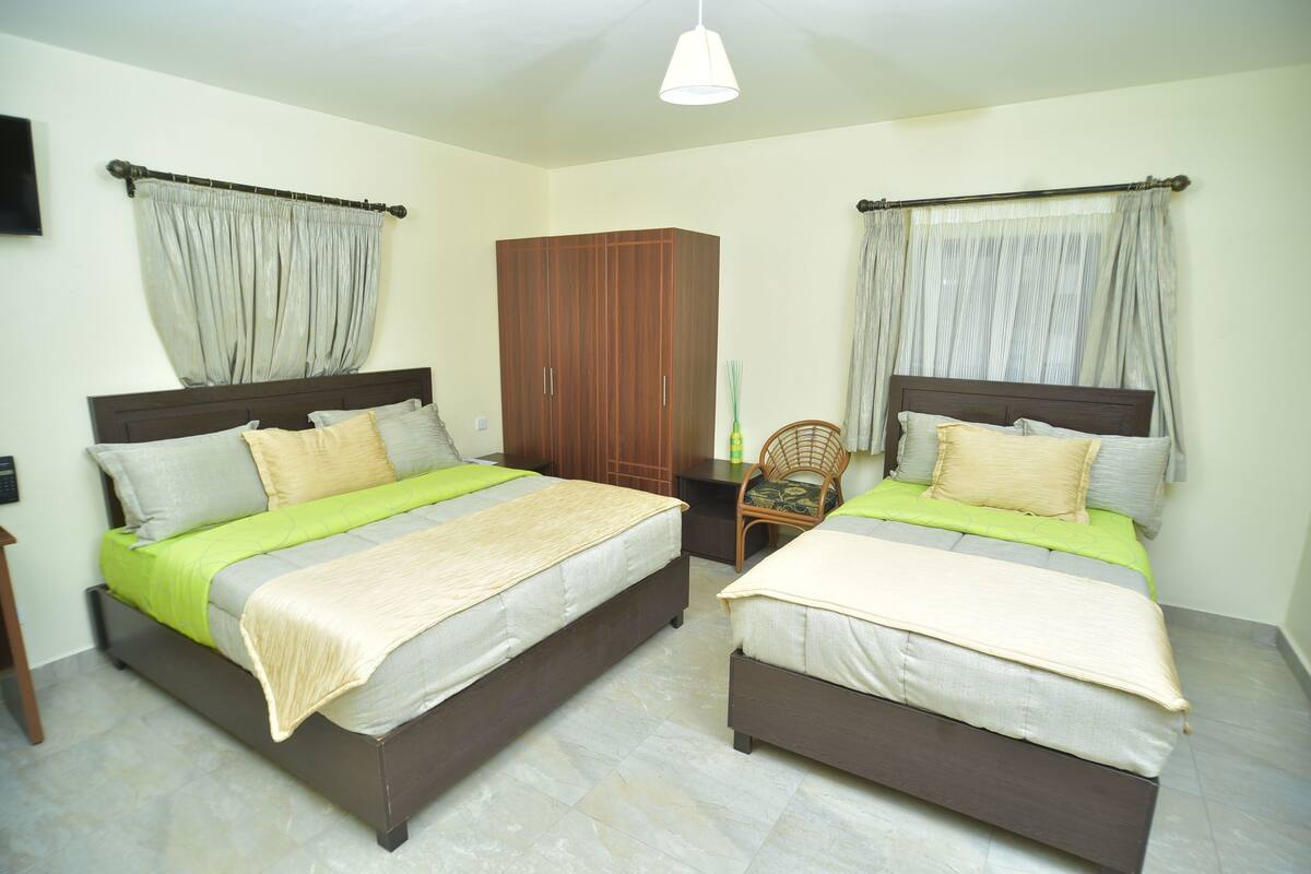 A double room with two beds, a wardrobe, and a chair.
